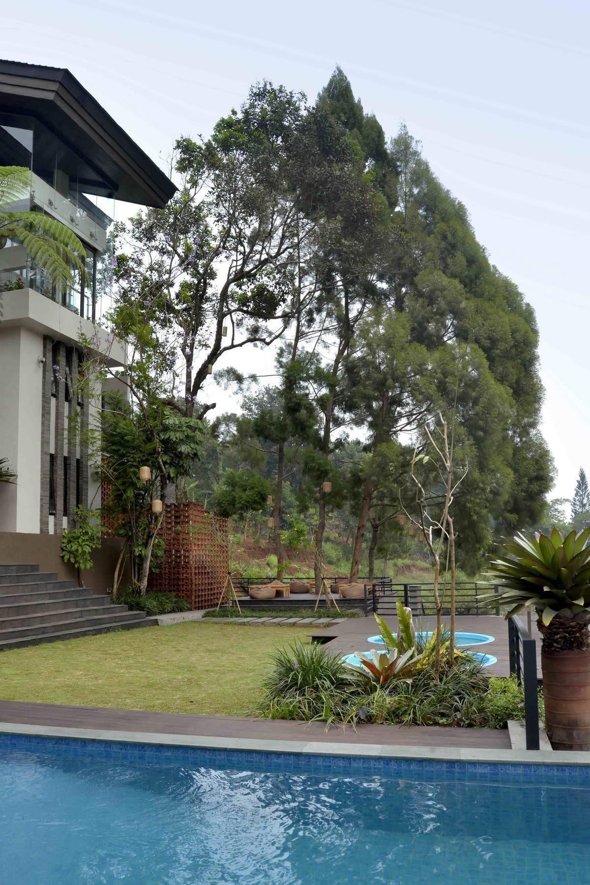Kolam vila VANA SHANKARA dengan bangunan berlantai dua dan halaman rumput di sisinya