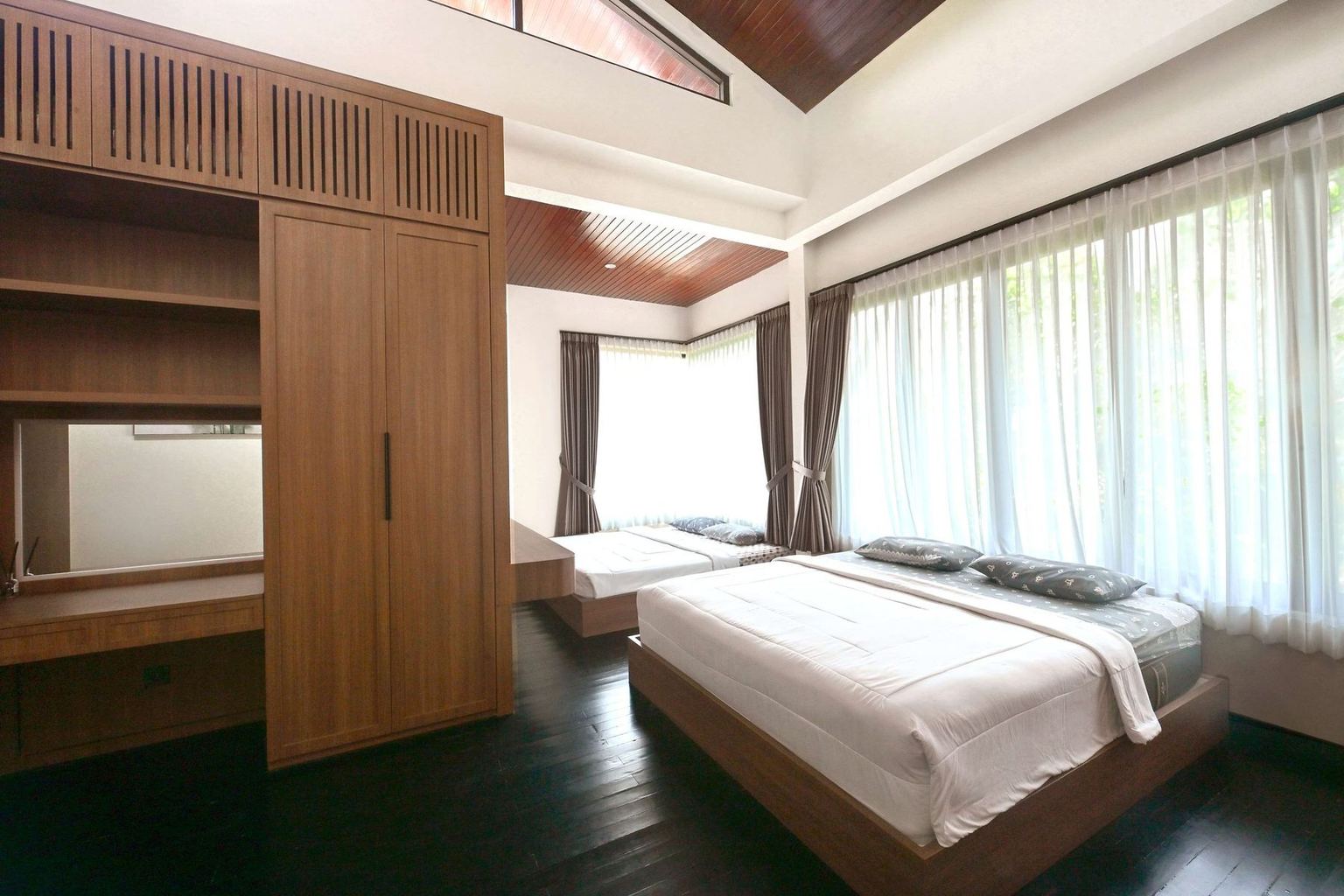 Kamar vila dengan dua tempat tidur, lemari kayu, dan jendela bertirai tipis