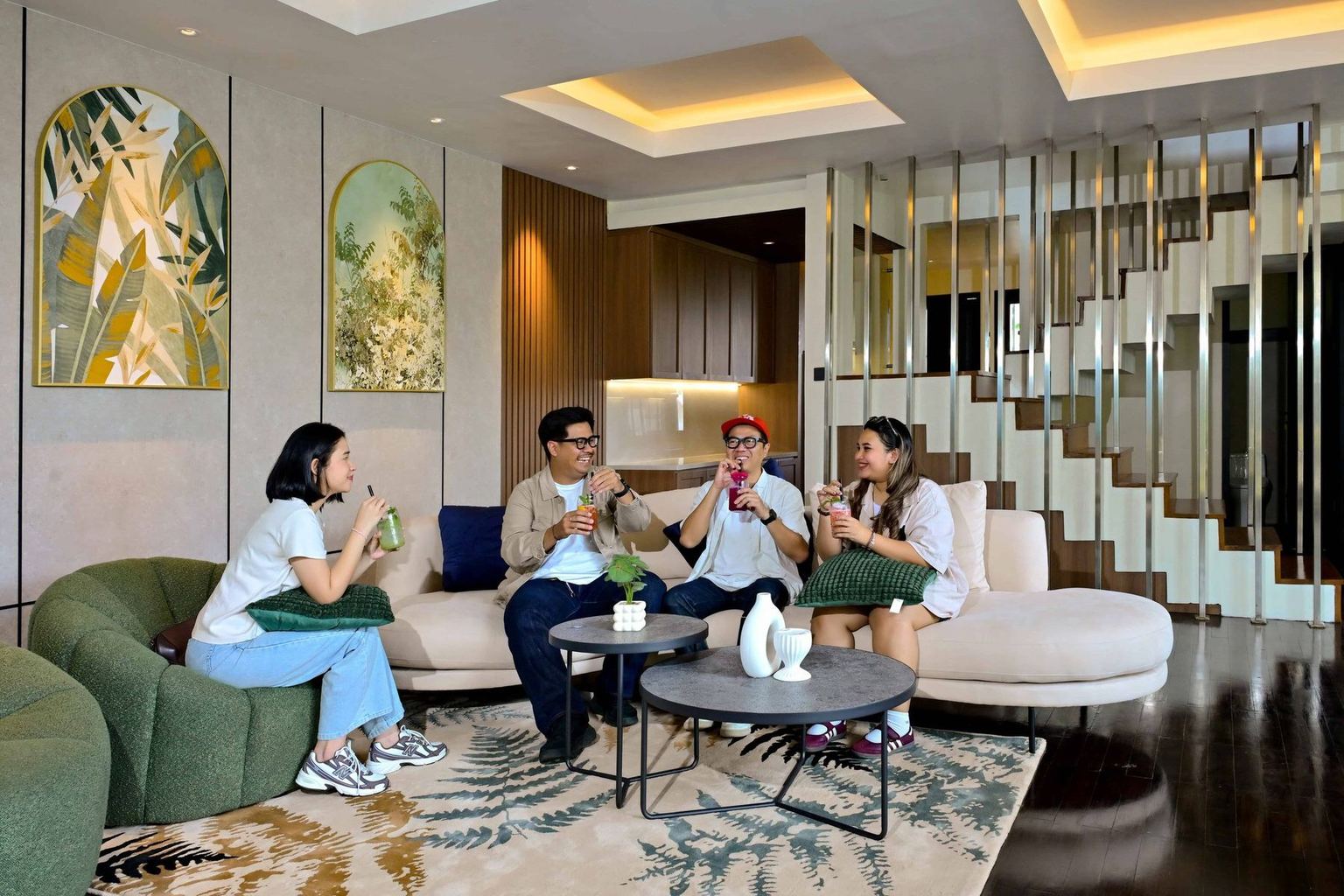 Tamu duduk bercakap di ruang tamu vila VANA SHANKARA dengan sofa krem dan karpet bermotif