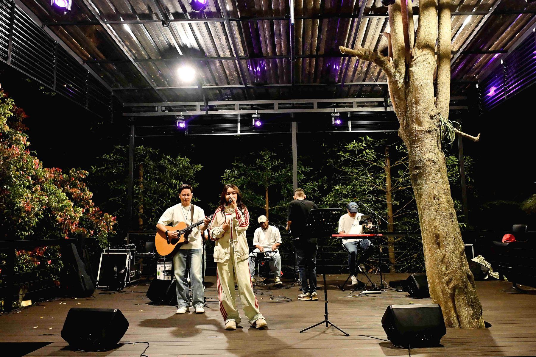 Band tampil di panggung terbuka VANA SHANKARA pada malam hari dengan lampu taman