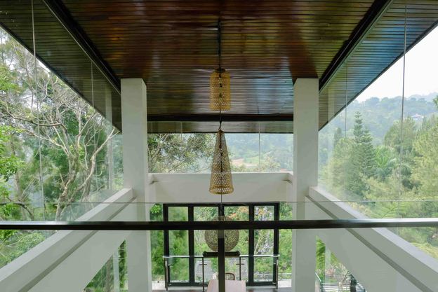 Koridor kaca VANA SHANKARA dengan lampu gantung dan pemandangan lembah