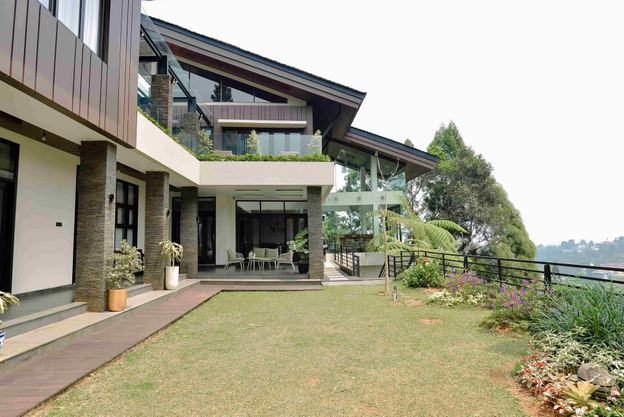 Fasad vila dua lantai VANA SHANKARA dengan halaman rumput dan latar perbukitan