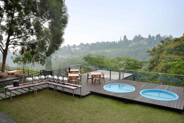 Dua circle pool di halaman rumput vila VANA SHANKARA dengan pepohonan dan lembah
