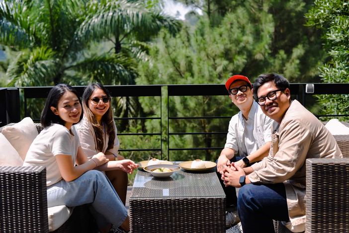 Tamu berbincang di sofa rotan teras VANA SHANKARA dengan latar pepohonan