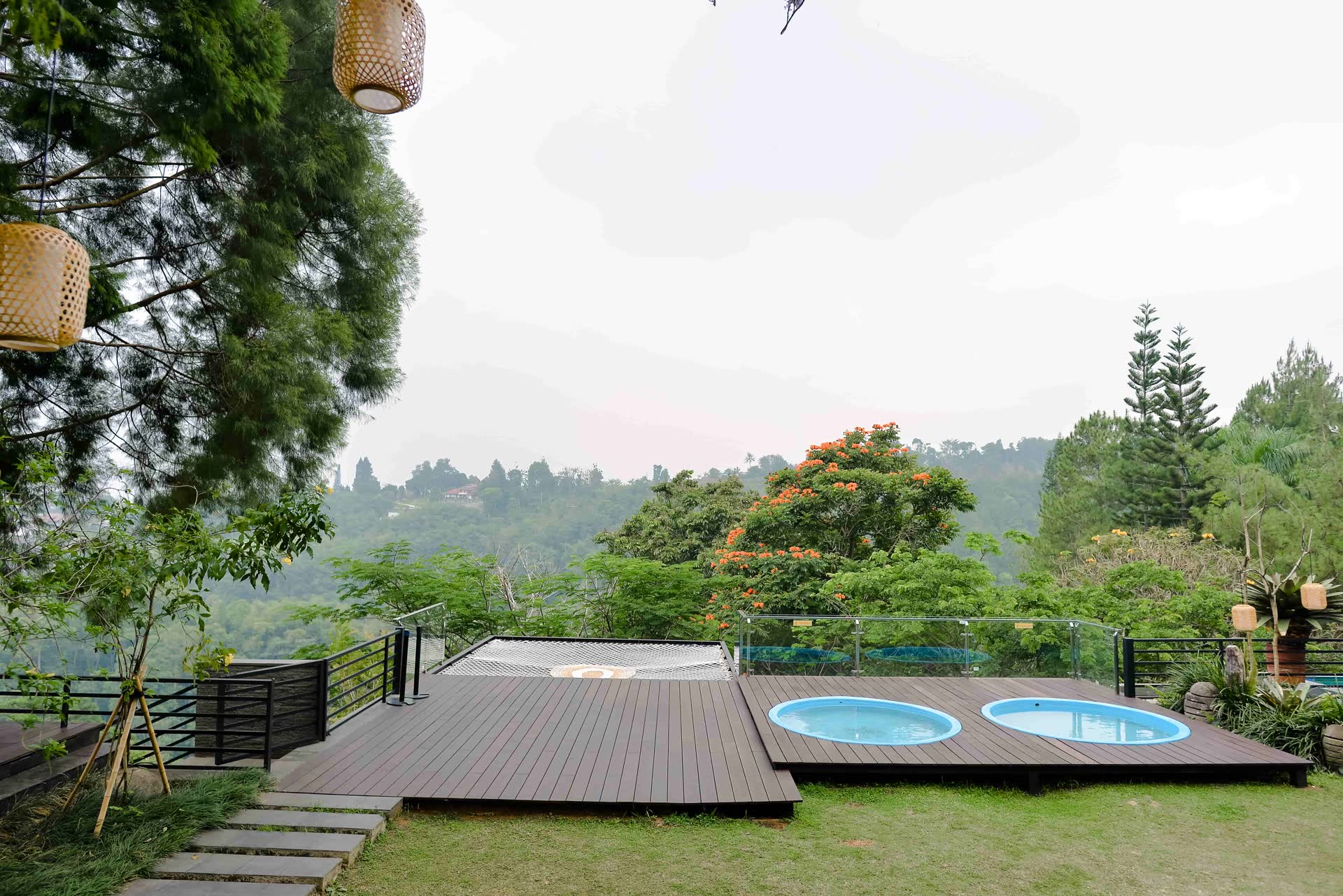Dek kayu dengan dua kolam bundar menghadap lembah dan pepohonan di VANA SHANKARA